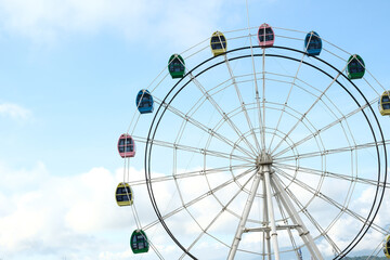 Ferris wheel against a blue sky, colorful patterns on the passenger cabins

