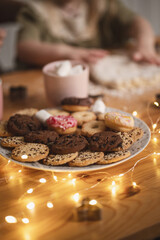muffins and Christmas cookies on the table among candles and garlands in Christmas tree toys and decorations. Noise blurred vintage film graine image
