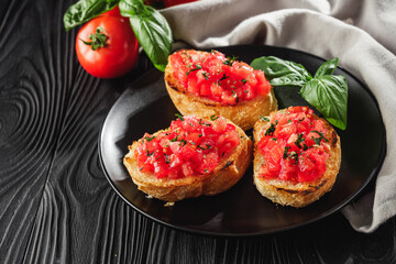 delicious Italian bruschetta with tomatoes on a black wooden rustic background