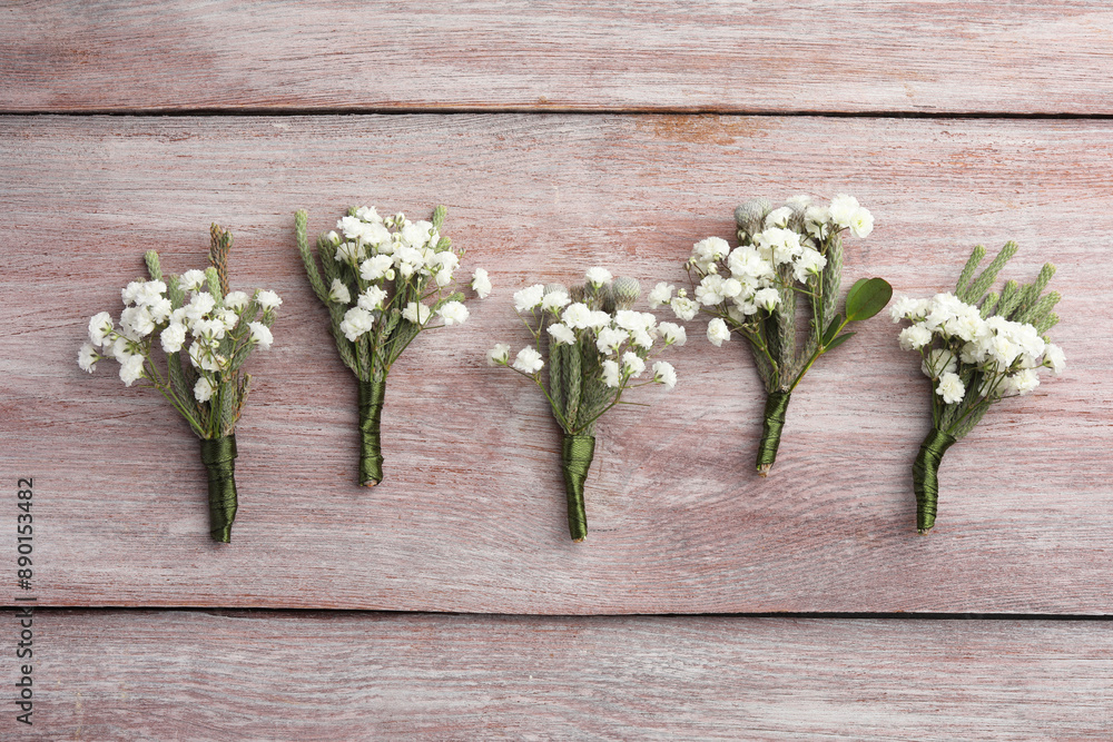 Canvas Prints Many small stylish boutonnieres on light wooden table, flat lay