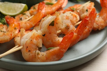 Skewers with delicious grilled shrimps served on plate, closeup