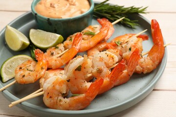 Skewers with delicious grilled shrimps served on white wooden table, closeup