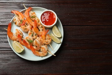 Skewers with delicious grilled shrimps served on wooden table, top view. Space for text