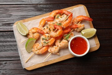 Skewers with delicious grilled shrimps served on wooden table, top view