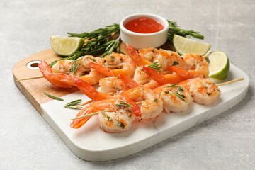 Skewers with delicious grilled shrimps served on grey table