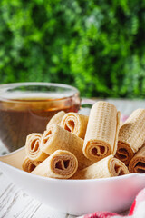 crispy dessert wafer rolls on a white wooden rustic background