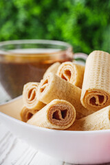 crispy dessert wafer rolls on a white wooden rustic background
