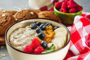 tasty nutritious oatmeal with fruits and berries on a light stone background