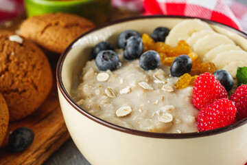 tasty nutritious oatmeal with fruits and berries on a light stone background