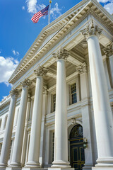 A majestic government building with grand columns and an American flag waving on a clear day, symbolizing democracy and authority.
