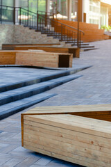 street side exterior aesthetic design elements pavement floor stairs building facade and square shape wooden benches clean outdoor urban landmark empty pleasure space, vertical picture with sun glare