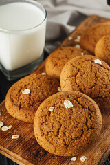 oatmeal cookies with a glass of milk on a black wooden rustic background