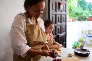Mother and daughter cooking together in the kitchen preparing food and enjoying family bonding time