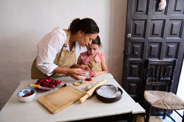 Mother and daughter baking together in kitchen, enjoying family time and homemade recipes