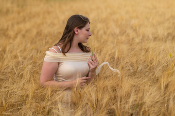woman is standing in a field of tall golden wheat