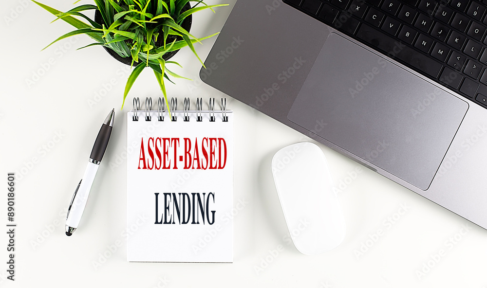 Poster asset-based lending text on a notebook with laptop, mouse and pen .