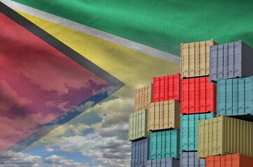 Guyana flag and big stack of shipping cargo containers in docks with sky background close up