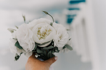 A bouquet of white flowers is being held by a person. The flowers are arranged in a way that they are not too close to each other, giving the impression of a beautiful and elegant arrangement.
