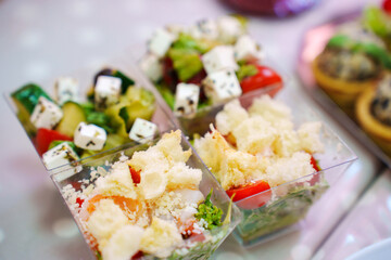 Portioned Greek salad and seafood salad for a banquet. Convenient serving of appetizers at a buffet table.