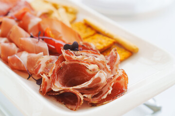 A plate with cold cuts and breadsticks. A delicious jerky appetizer.