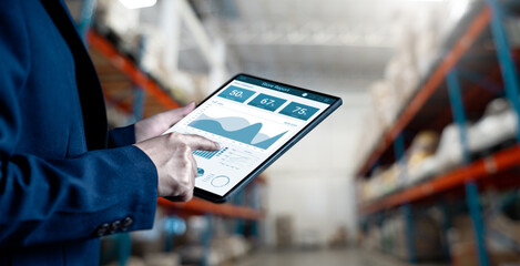 Businesswomen use tablet working for analysis of business report dashboards for the stock inventory, a Smart warehouse management system, supply chain and logistic network technology concept..