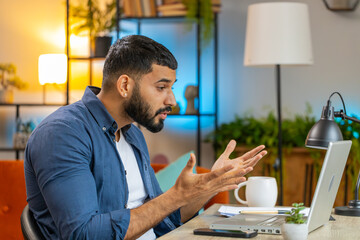 Angry furious Indian man freelancer using laptop while working at home office table having nervous breakdown at work, stress management, mental distress problems, losing temper, reaction on failure.