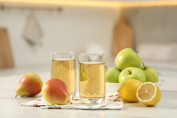 Glasses of fresh juice and fruits on white marble table in kitchen