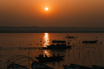 Boats and birds during dawn on sacred river Ganges in Varanasi, India