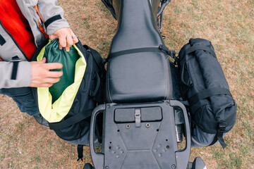 motorcyclist hands packing bags on Adventure motorcycle in moto tour outdoor