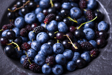 Fresh blueberries, blackcurrant berries and mulberries in a black plate close up. Food photography