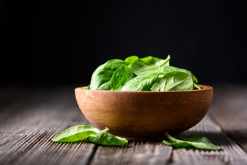 Baby spinach leaves in a wooden bowl on rustic wooden table. Food photography