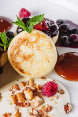 cottage cheese pancakes with berries and jam on a white plate
