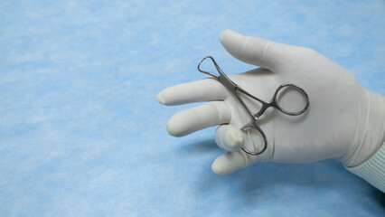 Hand in white glove hold towel clamps. This stainless steel towel clamps  used in surgery. Surgical...