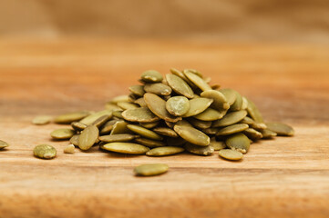Hulled pumpkin seeds on wooden surface