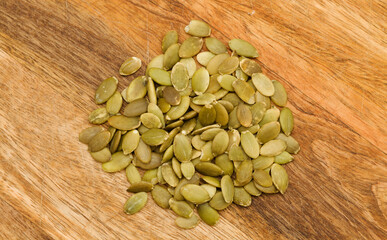 Hulled pumpkin seeds on wooden surface