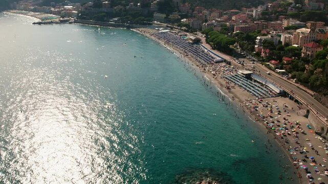 Drone shot tilting up to the crowded beach of Celle Ligure in the Italian region Liguria