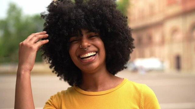 Smiling african woman smiling at camera outdoors - Portrait of curly afro american female laughing outside - Happy people life style concept - 4K Video