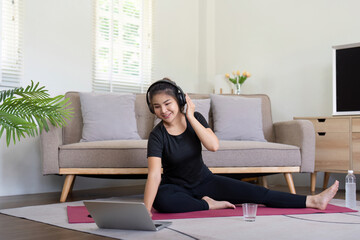 Young Woman Exercise at Home with Laptop and Headphones in Modern Living Room