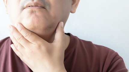 Fototapeta premium Man touching his neck with a concerned expression. Closeup view highlighting skin texture and hand detail