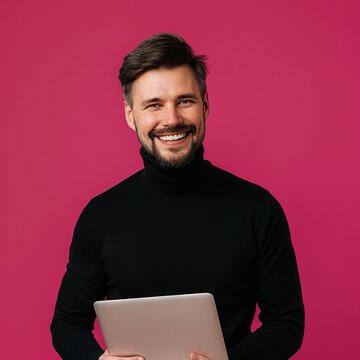 Smiling Man Holding a Laptop in Front of a Pink Background