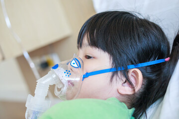 Sick little asian girl inhalation with nebulizer for respiratory treatment