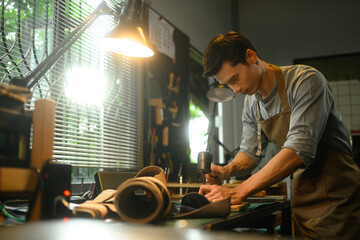 Focused craftsman intently working on a leather project in his local workshop