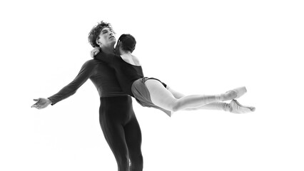 Ballet dancers dedicated to perfecting their moves together against white studio background. Black and white filter. Concept of pair training, classic ballet, inspiration, beauty, creativity. Ad.