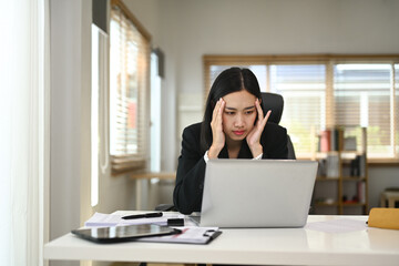 Youn businesswoman experiencing stress while working on her laptop in a modern home office