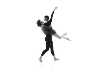 Focused and poised duo ballet dancers elegantly moves during training session against white studio background. Black and white filter. Concept of pair training, classic ballet, beauty, creativity. Ad.