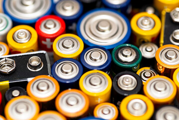 Background made of various alkaline and lithium-ion batteries, positive pole visible.