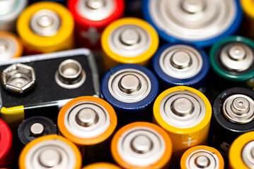 Background made of various alkaline and lithium-ion batteries, positive pole visible.