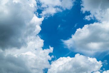 A clear blue sky filled with fluffy white clouds, creating a serene and peaceful atmosphere. The clouds vary in size and shape, adding texture and depth to the sky.