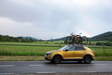 Samochód osobowy, SUV z rowerami na dachu w tle tęcza nad górami. © Stanisław Błachowicz