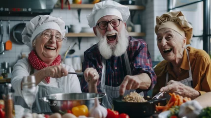 Three cheerful elderly chefs cooking together in a kitchen while laughing, enjoying their time, senior cooking concept © Aksana